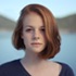 red-headed woman facing the camera in a front-profile with a blurred out background